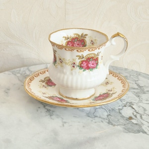 Damkopp och fat av elisabetanskt fint benporslin, England, dekorerad med ett brunt mönster av rosa rosor och vita blommor, och kantad med guld, 1980-talet