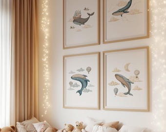 May include: Four framed watercolour prints of whales, hot air balloons, and clouds hang on a white wall. The artwork has a soft colour palette of blues, tans, and greys. A bed with teddy bears and pillows is in front of the wall.