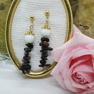 May include: A pair of dangle earrings with a white bead and a cascade of dark purple and black gemstone chips.
