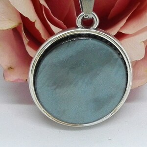 May include: A silver pendant with a round, grey glass insert. The pendant is on a silver chain.