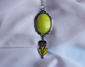 May include: A silver necklace with a yellow oval pendant and a charm of a cartoon character wearing a yellow dress.