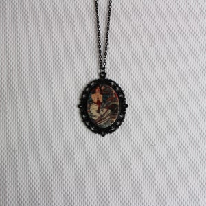 May include: A black chain necklace with a round pendant featuring a vintage illustration of a woman in a red dress. The pendant has a black filigree border.
