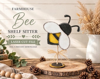 Puede incluir: Una figura de abeja de madera para estante con cuerpo a rayas amarillas y negras y alas blancas, montada sobre un palo de madera fino y una base circular. Un lazo de rafia rodea el palo. El texto dice: FARMHOUSE Bee SHELF SITTER LASER CUT FILE.