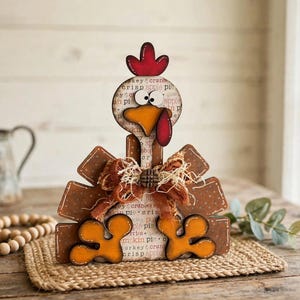 Pu&ograve; includere: Una statuetta decorativa di tacchino in legno con cresta rossa, becco giallo e bargiglio rosso. Il corpo &egrave; decorato con testo che riporta pumpkin pie, apple pie e cranberry crisp. Include un fiocco in tessuto marrone e piedi arancioni.