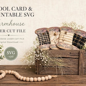 May include: Four vintage-style spool cards wrapped in fabric, featuring text that reads COLD SPRINGS MERCANTILE and FRIPPERY NEEDFULS. The spool cards are displayed in a rustic wooden crate, accented with small white flowers and safety pins.