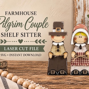 May include: Two wooden shelf sitter figures depicting a pilgrim couple. The male figure wears a brown hat and shirt with buttons, while the female figure wears a bonnet and a red and white checkered apron. Text reads FARMHOUSE Pilgrim Couple SHELF SITTER.