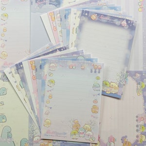 May include: A selection of Sumikkogurashi stationery in pastel shades. The stationery includes lined writing paper decorated with cartoon characters, stars, and other designs. The text "Sumikkogurashi" is visible on some sheets.