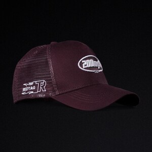 May include: A burgundy baseball cap with a mesh back and a curved brim. The cap features white embroidered text on the front and side, including the words "200m" and "REDTAG". The hat is designed for casual wear.
