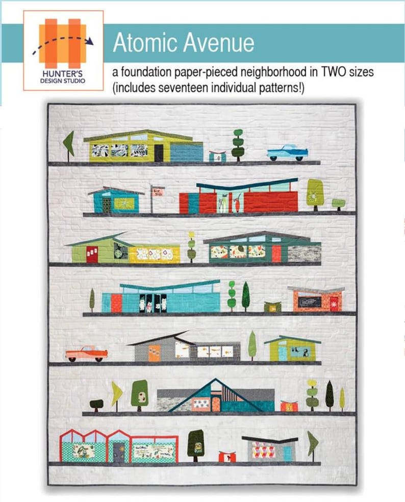 Op de afbeelding: Een stoffen quilt met een modernistische wijk uit het midden van de eeuw. De quilt toont kleurrijke huizen, bomen en auto's, met de tekst "Atomic Avenue" en "Hunter's Design Studio". Het ontwerp bevat zeventien individuele patronen.