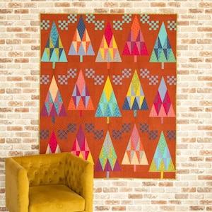 May include: A rectangular quilt featuring a repeating pattern of stylized triangular trees in various colors including pink, yellow, blue, and orange. The trees are arranged on a textured, burnt orange background with small blue square accents.