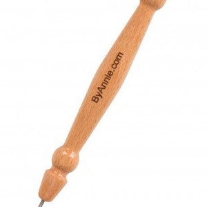 May include: A wooden tool with a pointed metal tip and a wooden handle with the text "ByAnnie.com" engraved on it. The tool is used for crafting and sewing.