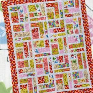 May include: A quilt pattern called "Bundle of 10" featuring a patchwork design with red, yellow, pink, and white fabric. The pattern requires 10 fat quarters and 2 contrast yards of fabric.