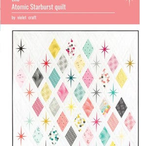 May include: A white quilt with a black border featuring a diamond pattern in various colors, including pink, yellow, teal, and gray. The quilt has starburst designs and the text "the Atomic Starburst quilt by violet craft".