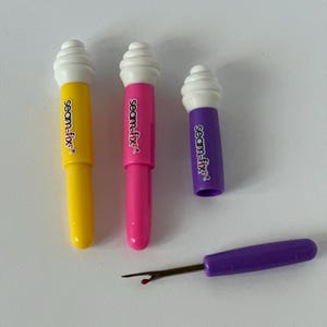 May include: Three colorful seam rippers with white tops and the text "seam-fix" on the side. A purple seam ripper with a red tip is also included.