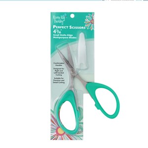 May include: Green and silver scissors with a white blade cover. The package reads "PERFECT SCISSORS" and "4 3/16" Small Knife-Edge Multipurpose Blades". The scissors have comfortable handles and are designed for right and left-handed cutting.