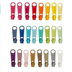 May include: A collection of twenty-four zipper pulls arranged in three horizontal rows, featuring a diverse spectrum of colors including red, orange, yellow, green, blue, purple, pink, brown, gray, and white. The text "Spring" is below.