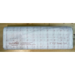 Puede incluir: Un rollo de entretela blanca Quiltsmart 2" Pix Smart Grid con un patrón de cuadrícula rojo impreso. El texto dice: Quiltsmart, 2" Pix Smart Grid, 9 x 16 grid (plus bonus top row), (144) 2" finished squares, Panel finishes approximately 34,3 cm x 61 cm.