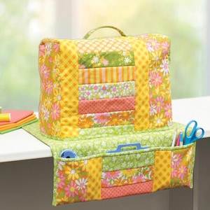 May include: A quilted sewing machine cover and accessory organizer. The cover is a patchwork of yellow, orange, green, and pink floral and geometric patterns. The organizer has pockets for tools and a handle for carrying.
