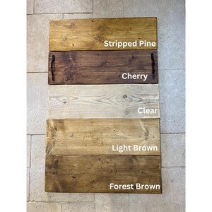 May include: Five wooden serving trays in different wood stains. The stains are, from top to bottom: Stripped Pine, Cherry, Clear, Light Brown, and Forest Brown.