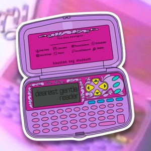 Op de afbeelding: Een sticker van een roze elektronisch dagboek met een scherm met de tekst "dearest gentle reader". Het dagboek heeft een toetsenbord, knoppen en de tekst "houston toy museum". De bovenkant van het dagboek heeft de tekst "This diary belongs to:" en pictogrammen.