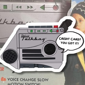 May include: A gray Deluxe Talkboy sticker with the text "CREDIT CARD? YOU GOT IT!" in a speech bubble. The sticker features a retro cassette recorder design with buttons and the words "Deluxe Talkboy" printed on it.