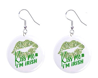 May include: A pair of white round earrings with a green and gold glitter lip print and the text "Kiss me I'm Irish".