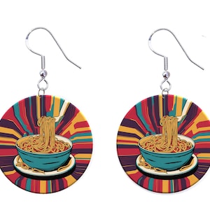 May include: A pair of round earrings featuring a retro-style illustration of a bowl of noodles. The earrings have a teal bowl with noodles being lifted by a fork, set against a colorful, striped background. The earrings hang from silver hooks.