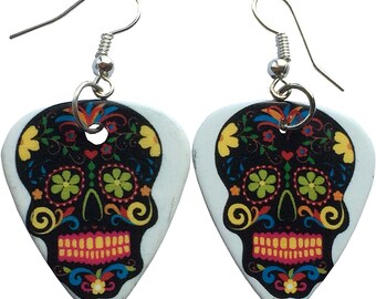 May include: A pair of silver earrings with a white guitar pick shaped pendant featuring a black and white sugar skull design with colorful floral details.