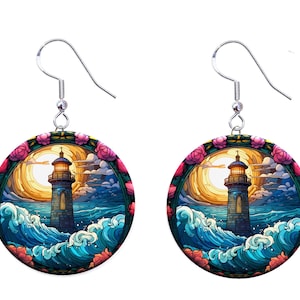 May include: A pair of earrings featuring a colorful stained glass design of a lighthouse with waves crashing against it. The lighthouse is surrounded by a circle of pink flowers. The earrings are silver.