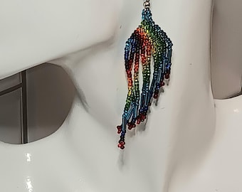 May include: Rainbow beaded dangle earrings with a silver hook. The earrings are made of small, colorful beads that are strung together in a cascading pattern.