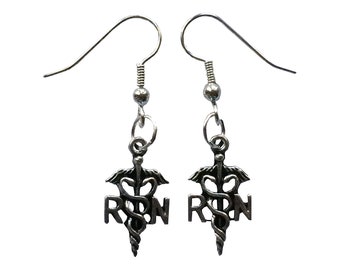 May include: Silver earrings with a medical symbol and the letters "RN" hanging from the bottom.