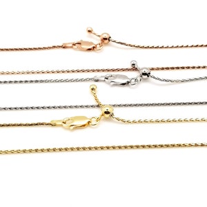 Puede incluir: Primer plano de cuatro collares ajustables de cadena de trigo en tonos oro rosa, plata y oro. Cada collar presenta un cierre de mosquet&oacute;n y una cuenta deslizante para ajustar la longitud. Las cadenas se muestran sobre un fondo blanco.