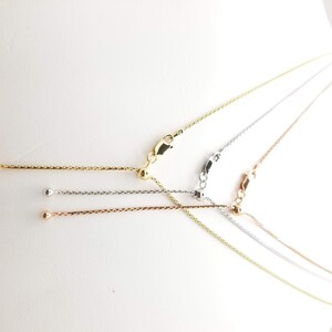 Puede incluir: Cuatro collares de cadena ajustables en tonos oro, plata y oro rosa. Cada collar presenta una delicada cadena con una cuenta deslizante para ajustar la longitud y un cierre de mosquet&oacute;n. Se muestran sobre un fondo blanco.