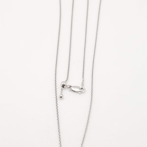 Puede incluir: Un collar ajustable plateado con una cadena delicada. El collar presenta una peque&ntilde;a bola y un cierre para ajustar la longitud. La cadena se muestra sobre un fondo blanco.
