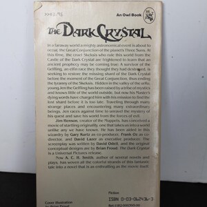 May include: A paperback book titled "The Dark Crystal" by A.C.H. Smith. The cover features the title in a stylized font, with text describing the plot and the author's name. The book is a Universal Pictures release.