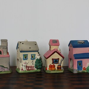 May include: Set of five Halloween-themed ceramic houses with various colors and details, including a ghost, pumpkins, and a fence.