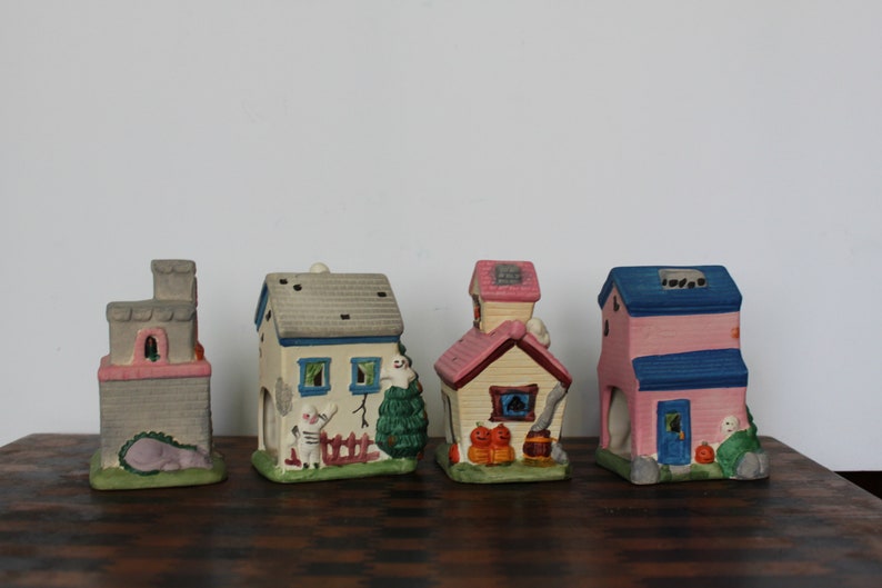 May include: Set of five Halloween-themed ceramic houses with various colors and details, including a ghost, pumpkins, and a fence.