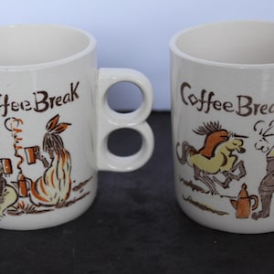 May include: Two off-white ceramic mugs with double-ring handles, each featuring the text Coffee Break and brown and yellow illustrations of historical figures. One mug depicts Boone, while the other shows Gen. Custer with a horse and coffee pot.