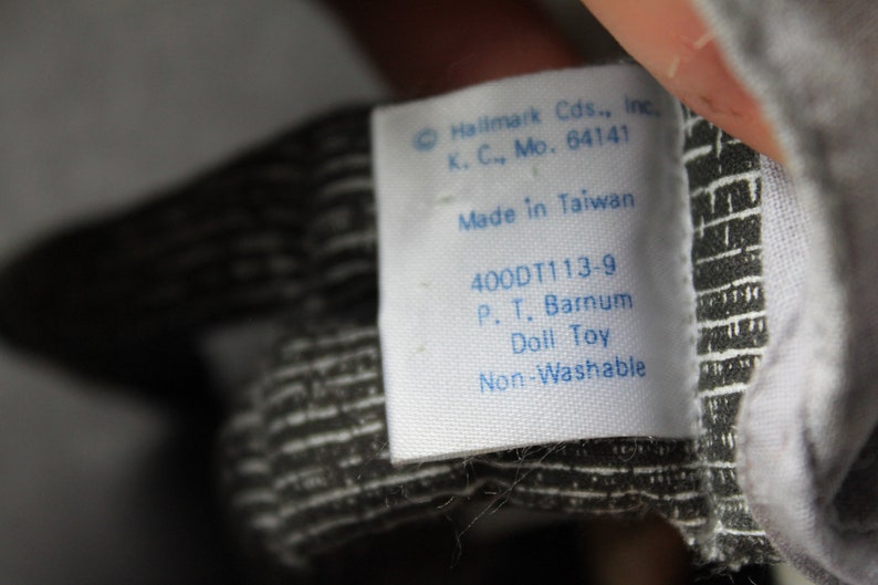 May include: White tag with blue text that reads "Hallmark Cds., Inc. K. C., Mo. 64141 Made in Taiwan 400DT113-9 P. T. Barnum Doll Toy Non-Washable"
