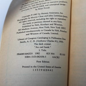 May include: A page from a book titled "The Dark Crystal" with text including copyright information, publisher details, and Library of Congress data. The text is in black font on a cream-colored paper. The book is a first edition.