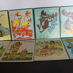 May include: Set of eight vintage cartoon character jigsaw puzzles. The puzzles feature characters like a moose, a blue rabbit, a blue dinosaur, and two mice in a fire truck. The puzzles are in good condition and have a light blue background.
