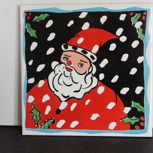 May include: A square ceramic tile featuring a vintage illustration of Santa Claus. Santa is depicted with a white beard and a red suit with white polka dots. The background is black with white snow-like shapes, and a blue border.