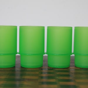 May include: Four green plastic cups with a frosted finish. The cups are stacked on top of each other.