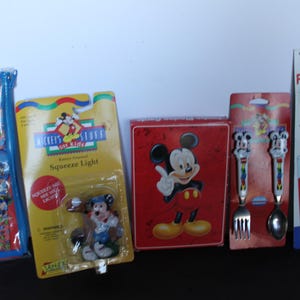 May include: A collection of Disney-themed merchandise, including a Mickey Mouse squeeze light, a red box with Mickey Mouse, a set of forks and spoons, and a Fun Straw. The items are in their original packaging.