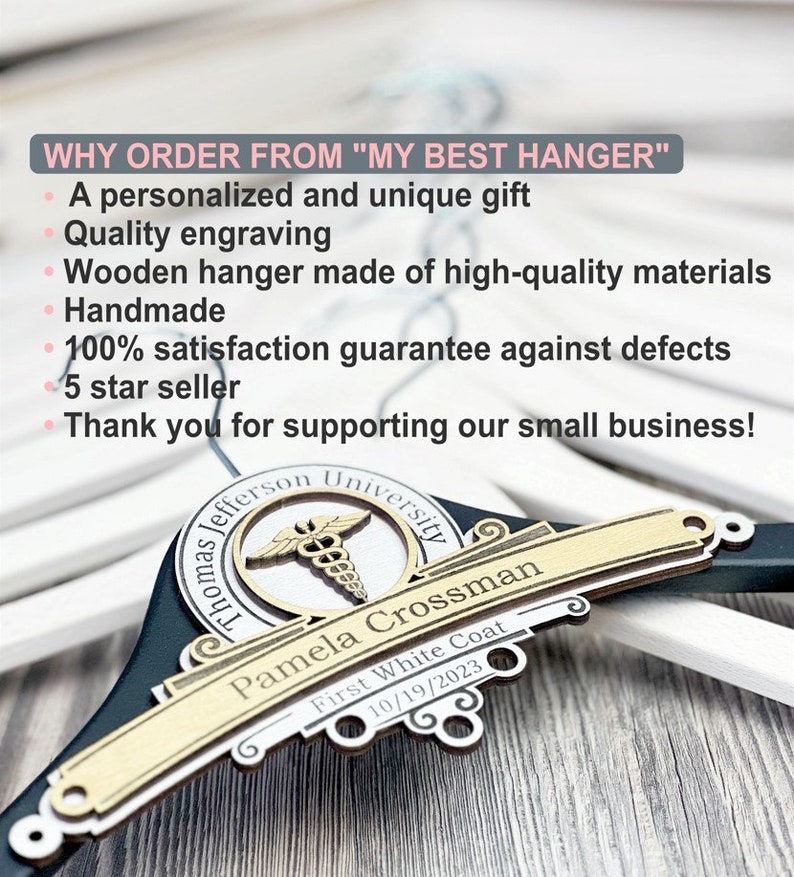 May include: A black wooden hanger featuring a decorative gold-toned plaque engraved with the text Thomas Jefferson University, Pamela Crossman, First White Coat, and 10/19/2023, along with a medical caduceus symbol centered above the name.