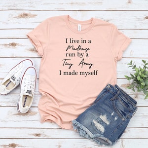 May include: A pink t-shirt with the text "I live in a Madhouse run by a Tiny Army I made myself" printed in black.