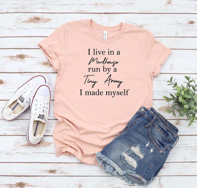 May include: A pink t-shirt with the text "I live in a Madhouse run by a Tiny Army I made myself" printed in black.