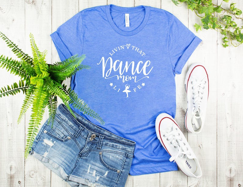 a casual outfit consisting of a blue t-shirt with white text, denim shorts, white sneakers, and a potted plant.