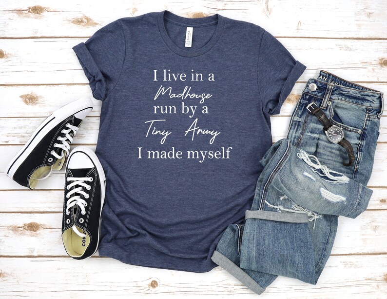 May include: A navy blue t-shirt with white text that reads "I live in a Madhouse run by a Tiny Army I made myself".