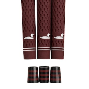 May include: Three maroon golf club grips featuring a textured surface with a repeating oval pattern and a white duck logo. Each grip includes two thin white horizontal stripes near the base. Three matching ferrules with black and maroon stripes.